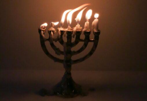 A seven-branch menorah with all candles lit and burned down almost to the end. Photo: Geraud Pfeiffer.