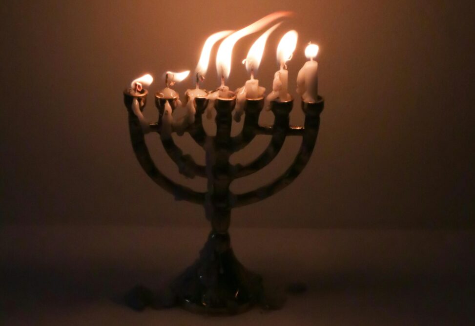 A seven-branch menorah with all candles lit and burned down almost to the end. Photo: Geraud Pfeiffer.